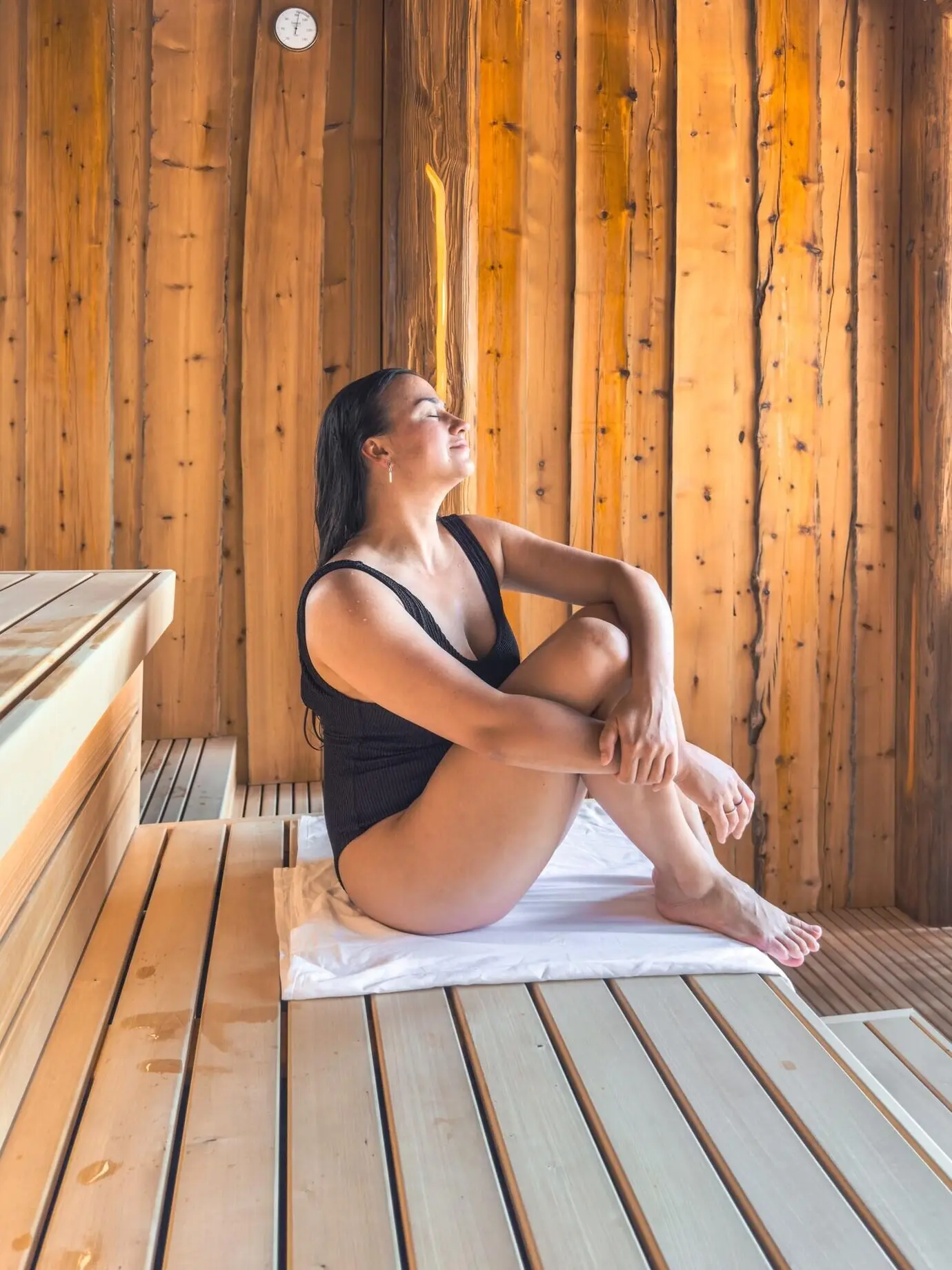 Eine Frau entspannt in einer Holzsauna, Ruhe und Wärme.